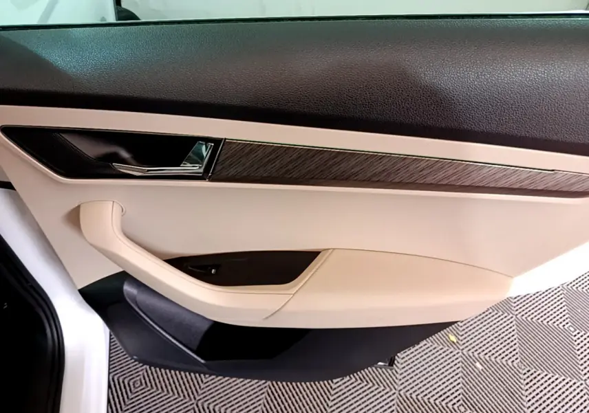 Gros plan sur la porte intérieure côté droit du Skoda Karoq blanc, avec garniture beige et insert bois foncé.
