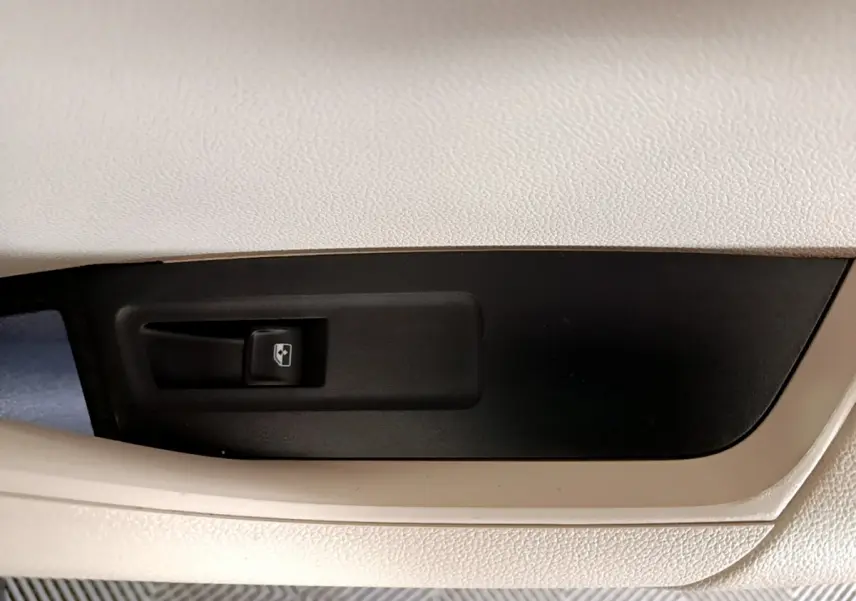 Gros plan sur le bouton de commande de vitre électrique, intérieur beige et noir du Skoda Karoq blanc 2023.