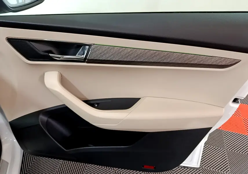 Intérieur côté gauche de la porte avant beige et noir avec insert bois sur Skoda Karoq blanc 2023.