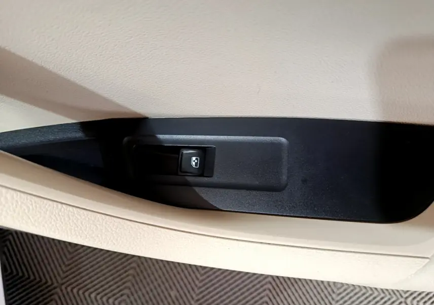 Gros plan sur le bouton de commande de la vitre électrique, intérieur beige et noir du SKODA KAROQ 2023.