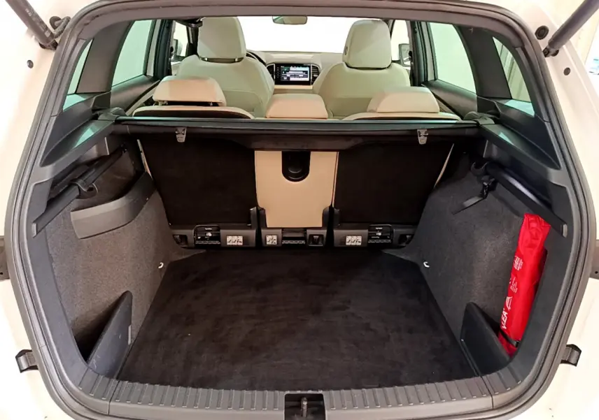 Coffre ouvert d’un Skoda Karoq blanc 2023, vue arrière montrant l’espace de chargement et les sièges beige.