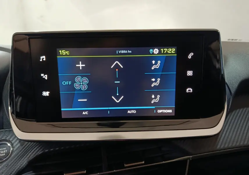 Écran tactile central allumé du tableau de bord d'une Peugeot 208 électrique blanche, vue intérieure frontale.