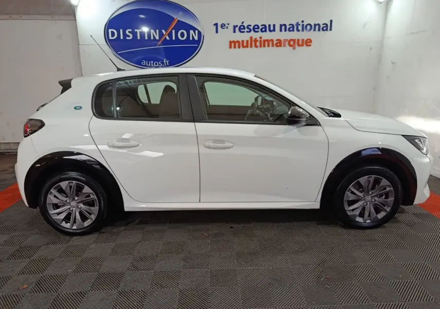 Profil droit d'une Peugeot 208 électrique blanche 2023, avec jantes alliage et détails noirs contrastants sur les passages de roues.
