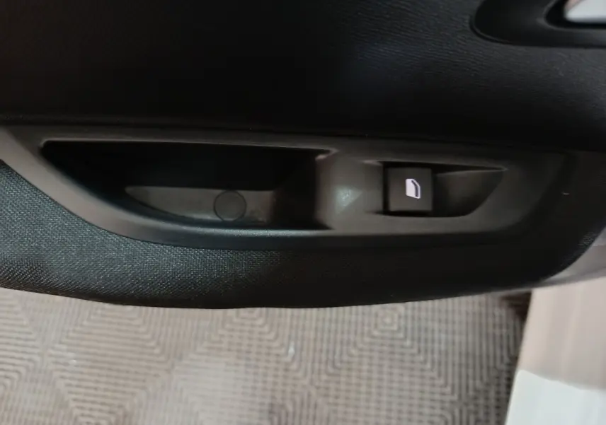 Bouton de verrouillage de porte noir sur panneau intérieur de porte d'une Peugeot 208 électrique blanche, vue rapprochée.