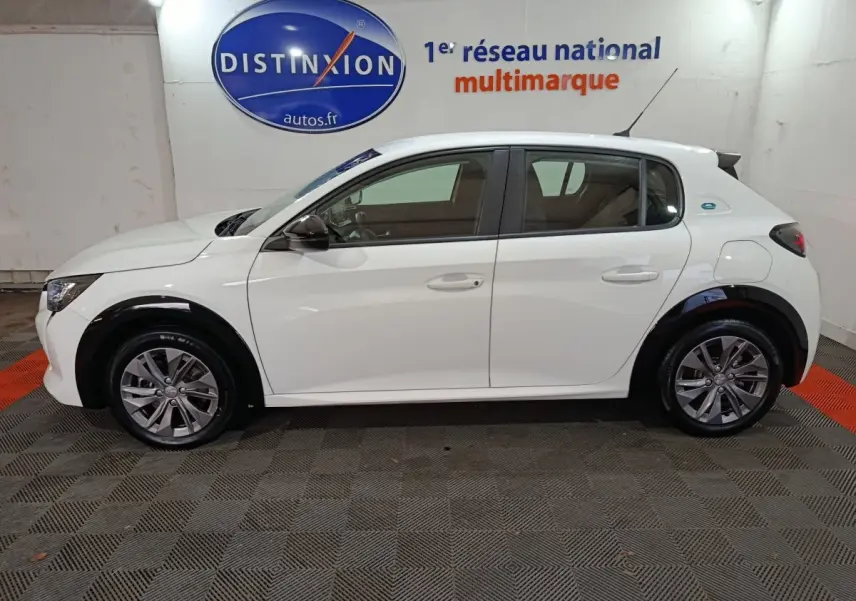 Peugeot 208 électrique blanc vue de profil côté gauche, avec jantes alliage et logo e-208 sur l'aile arrière.