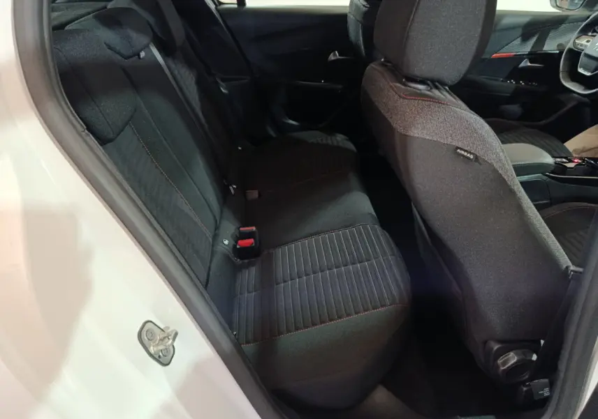 Vue intérieure côté gauche sur la banquette arrière noire avec surpiqûres rouges d'une Peugeot 208 électrique blanche 2023.