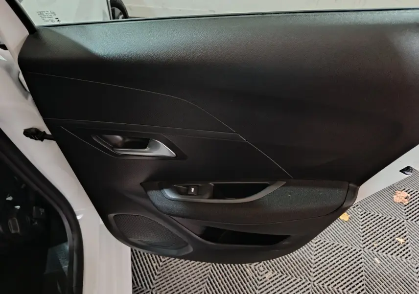 Vue rapprochée de la porte avant gauche noire d'une Peugeot 208 électrique blanche 2023 avec poignée intégrée.