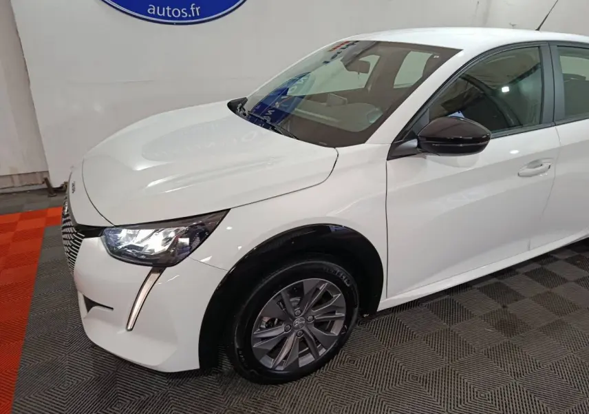 Vue 3/4 avant gauche d'une Peugeot 208 électrique blanche avec phares LED et rétroviseurs noirs brillants.