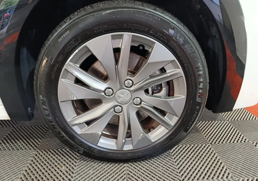Gros plan sur la roue avant droite blanche d'une Peugeot 208 électrique 2023 avec jante alliage et pneu Michelin.
