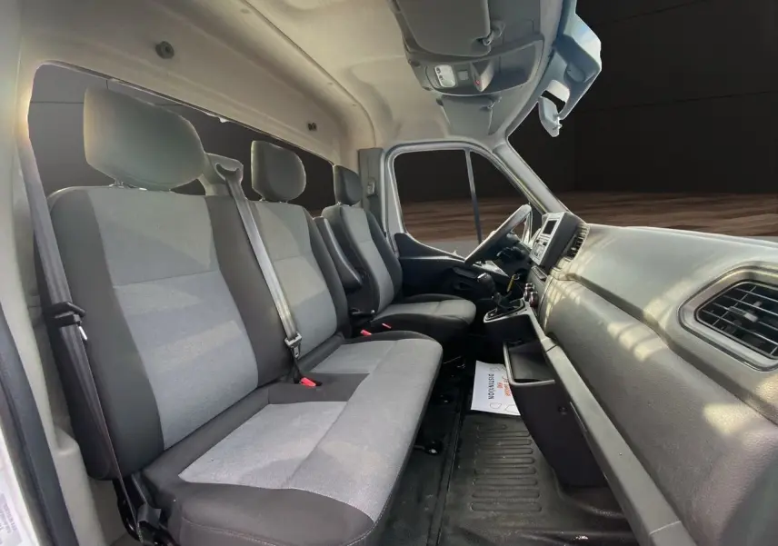 Vue intérieure côté passager du Renault Master 2024, montrant les sièges tissu gris et tableau de bord noir.