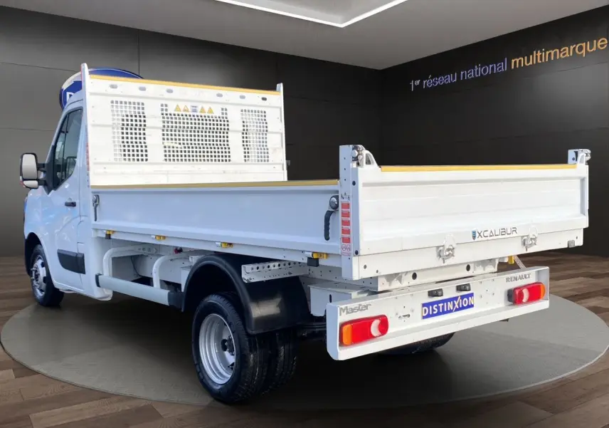 Vue 3/4 arrière droite d’un Renault Master blanc version benne, avec ridelles métalliques et cabine simple.
