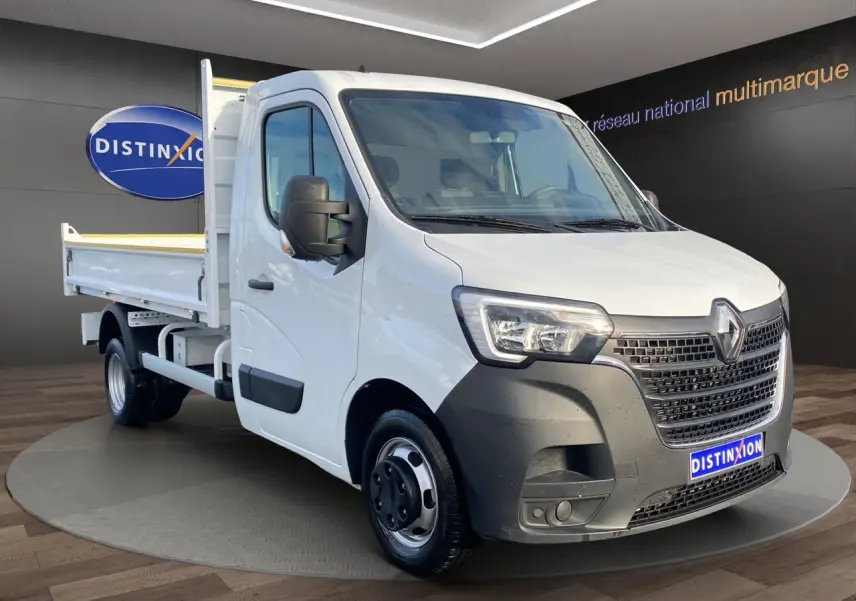 Renault Master blanc en 3/4 avant droit, benne arrière visible, calandre noire et phares LED distinctifs.