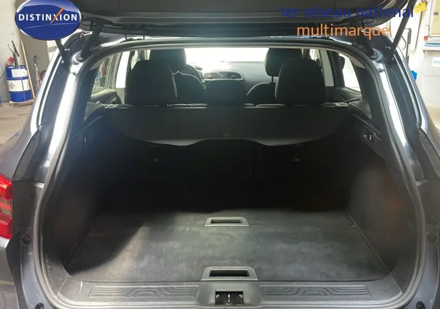 Coffre ouvert d'un Renault Kadjar bleu foncé métal vu de l'arrière, montrant l'espace de chargement vide et les sièges arrière.