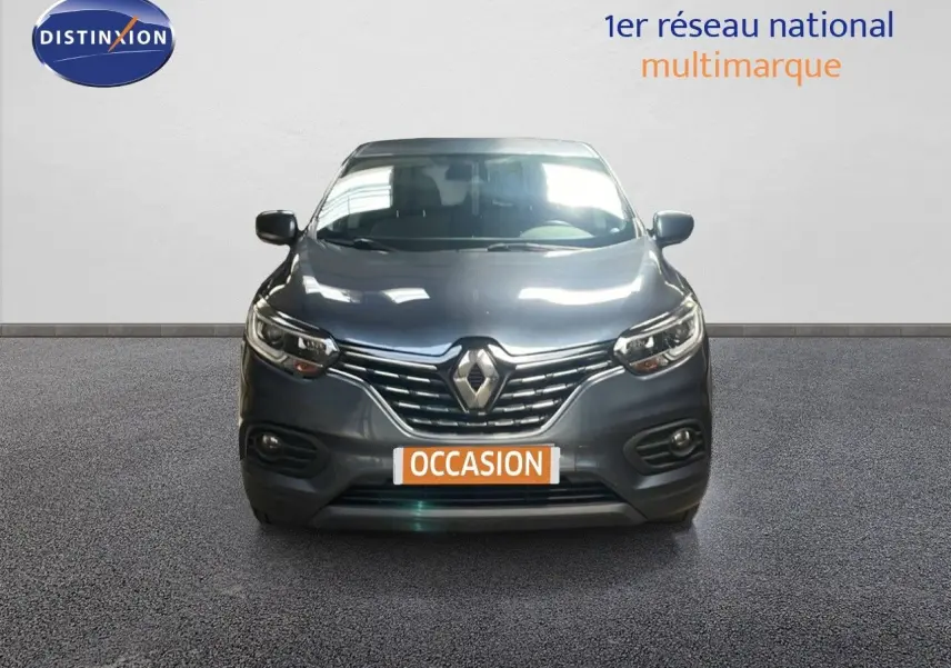Renault Kadjar bleu foncé métal vu de face, avec calandre chromée et phares LED allumés.