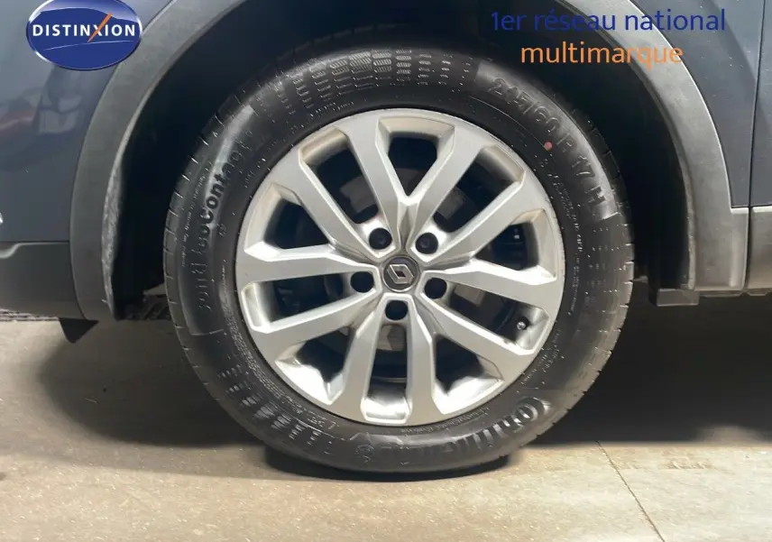 Gros plan sur la roue avant gauche d'un Renault Kadjar bleu foncé métal avec jante alliage distinctive.