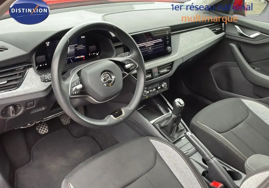 Vue intérieure côté conducteur du Skoda Kamiq 2024, montrant le volant, la boîte manuelle et les sièges tissu gris et noir.