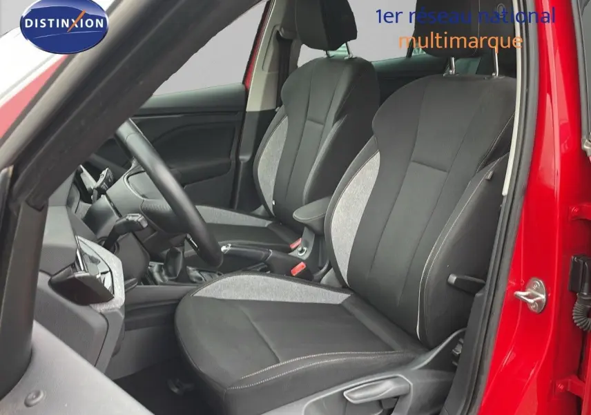 Vue intérieure côté conducteur d'une Skoda Kamiq 2024 rouge Velvet Metal, sièges tissu gris et noir avec coutures contrastées.