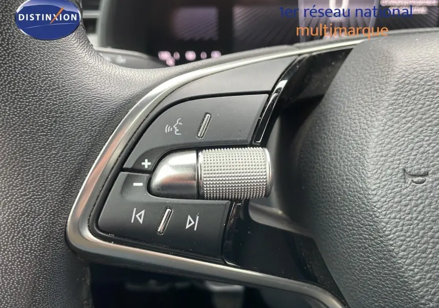 Gros plan sur les commandes du volant du Skoda Kamiq rouge velvet metal, mettant en valeur la molette et les boutons multifonctions.