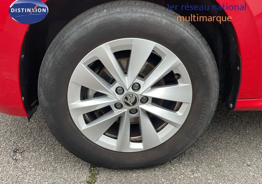 Gros plan sur la roue avant gauche d'un Skoda Kamiq rouge velvet metal avec jante alliage argentée.