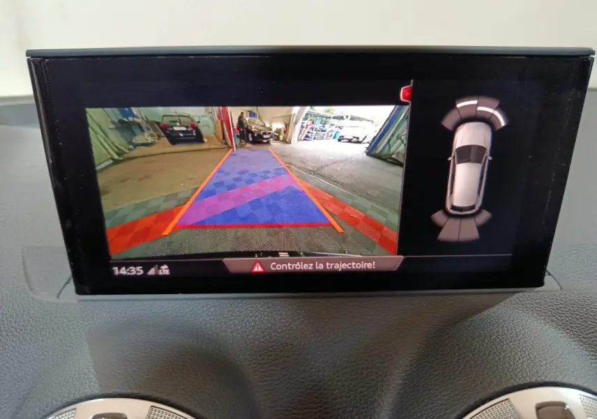 Écran intérieur de l'Audi Q2 noir 2022 montrant la caméra de recul avec guidage de trajectoire et capteurs de stationnement.