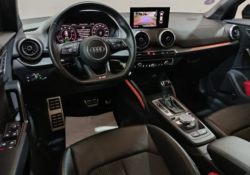 Intérieur noir de l'Audi Q2 35 TFSI 2022, vue côté conducteur sur volant, tableau de bord digital et console centrale.