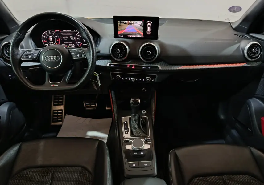 Vue intérieure de l'Audi Q2 35 TFSI S Line Plus 2022, tableau de bord noir avec écran central et volant multifonctions cuir.