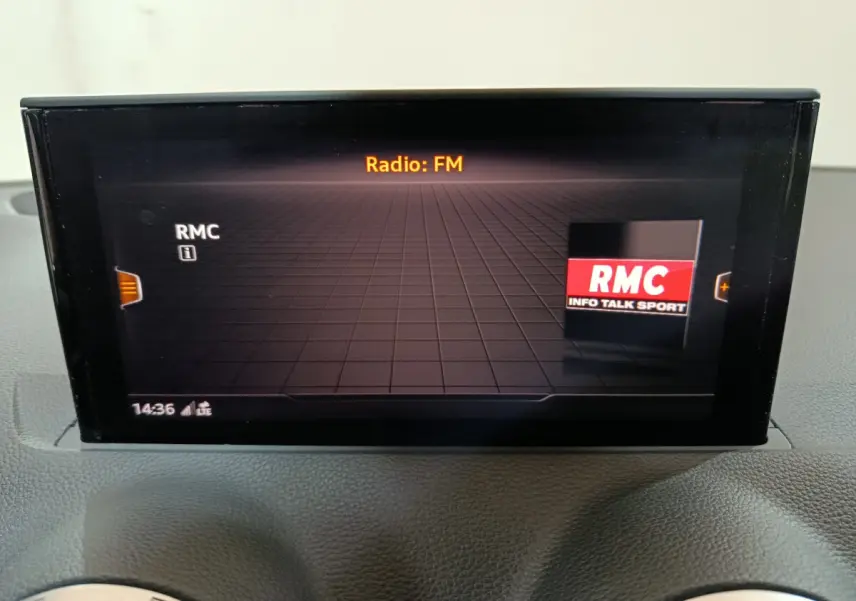 Écran tactile central affichant la radio FM RMC dans l'habitacle d'une Audi Q2 noire 2022.
