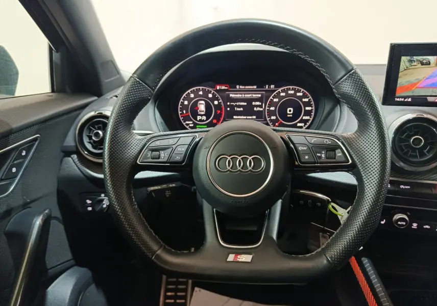 Vue frontale du volant cuir perforé avec logo Audi S Line, tableau de bord digital et écran de caméra de recul du Q2 noir 2022.