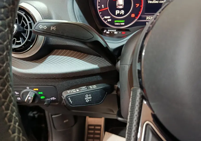 Gros plan sur le volant et commandes au volant de l'Audi Q2 35 TFSI noir, avec tableau de bord numérique visible.