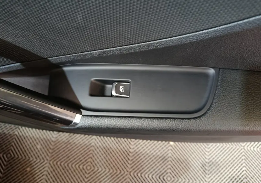 Gros plan sur le bouton de commande de vitre électrique côté gauche dans l'habitacle noir de l'Audi Q2 35 TFSI 2022.