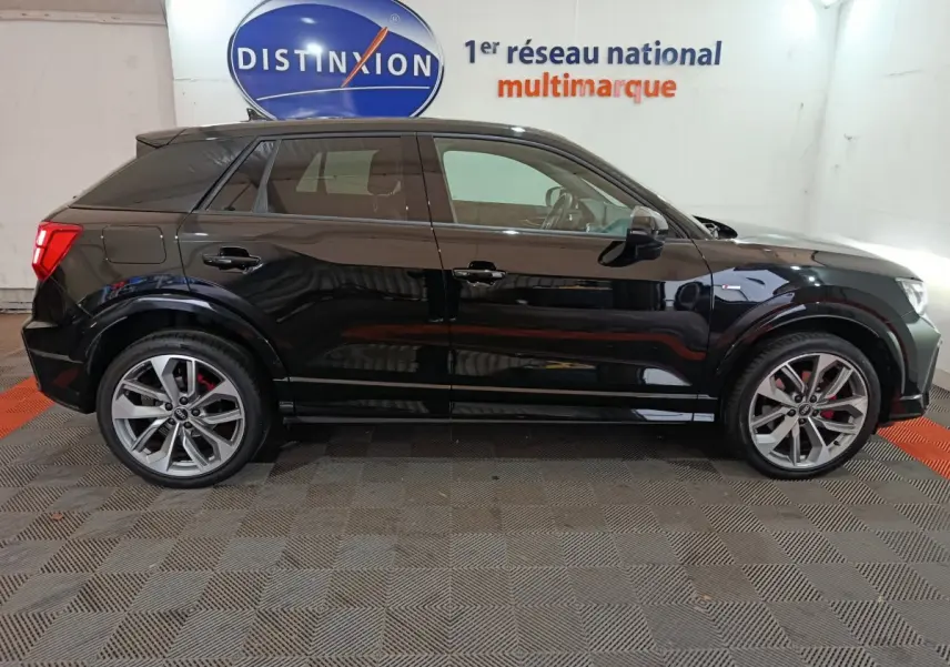Profil côté gauche d'un Audi Q2 noir 2022 S Line Plus, avec jantes alliage et étriers de frein rouges visibles.