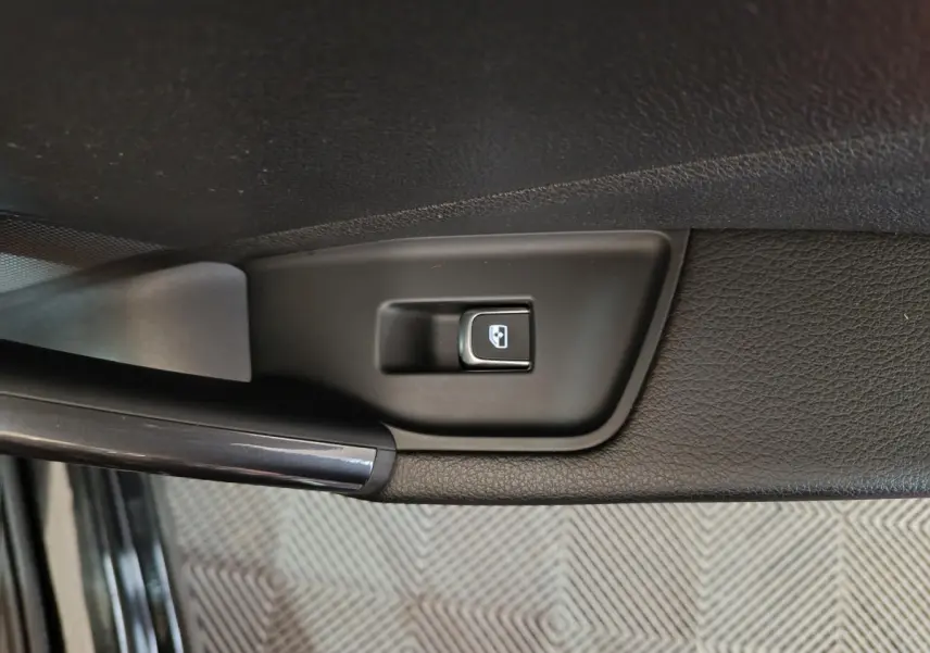 Bouton de commande de lève-vitre noir sur la portière intérieure côté gauche d'un Audi Q2 noir.