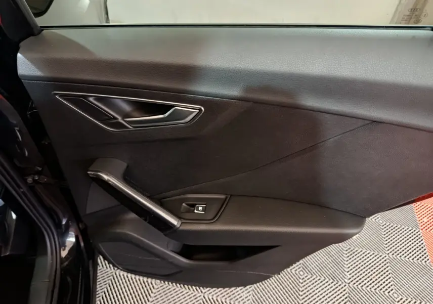 Vue latérale du panneau de porte intérieur noir de l'Audi Q2 35 TFSI 2022 avec poignée et bouton de verrouillage intégré.