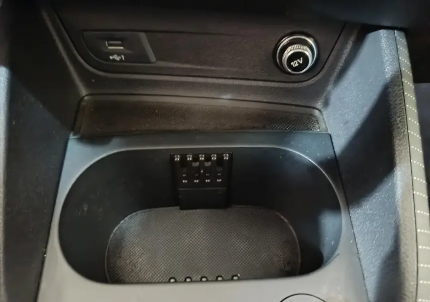 Gros plan sur la console centrale noire de l'Audi Q2 35 TFSI, avec prise 12V et port USB visibles.