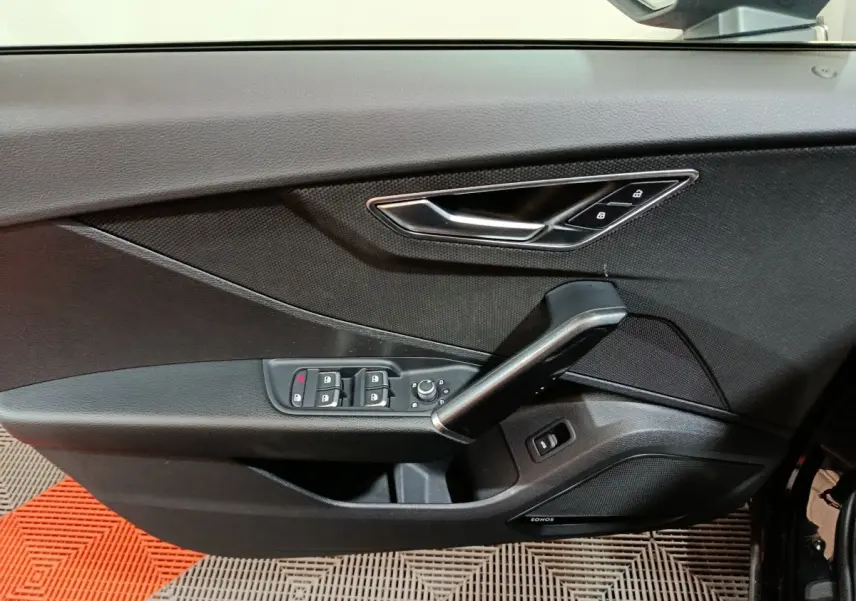 Vue rapprochée de la porte côté conducteur noire d'un Audi Q2 35 TFSI 2022 avec commandes de vitres et poignée argentée.