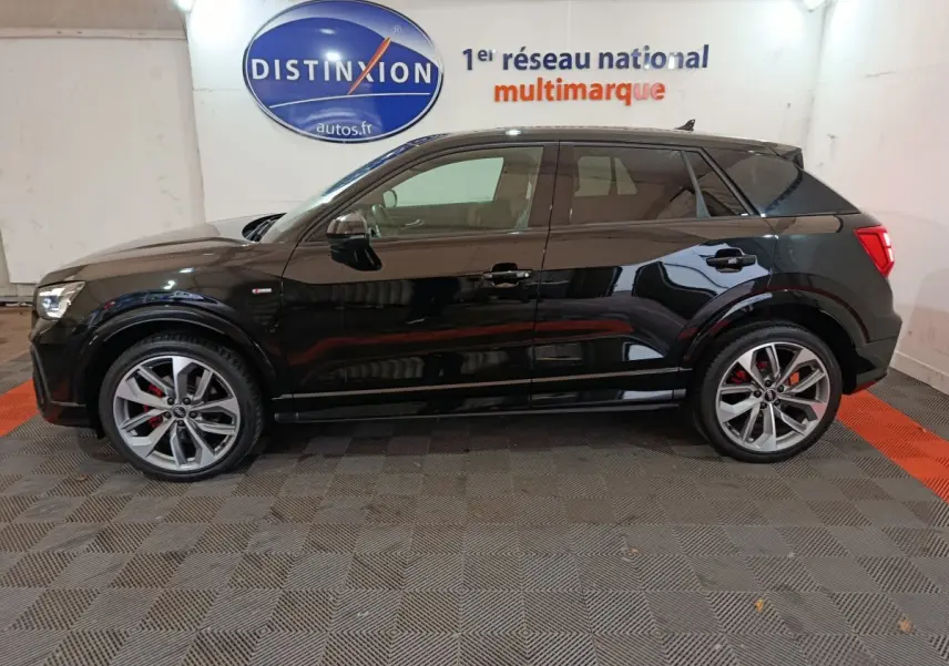 Profil côté gauche d'un Audi Q2 noir 35 TFSI S Line Plus 2022 avec jantes alliage et étriers rouges visibles.