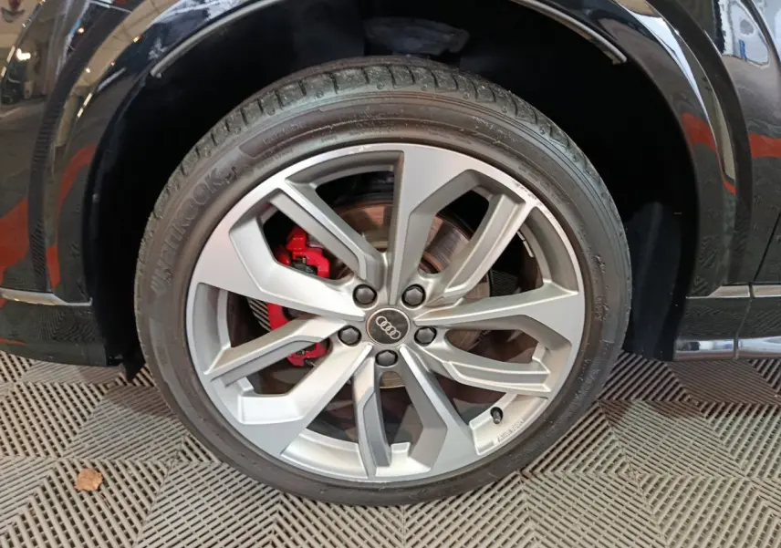Gros plan sur la roue avant droite d’un Audi Q2 noir, jante alliage argent avec étrier de frein rouge visible.