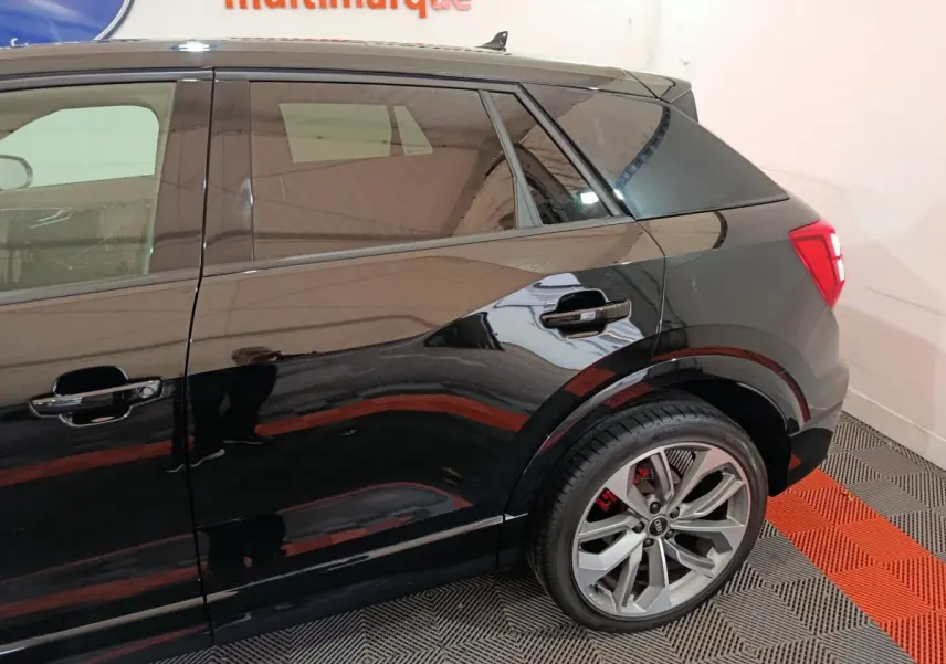 Vue latérale droite sur l'arrière d'un Audi Q2 noir 35 TFSI S Line Plus avec jantes alliage et feux arrière LED.