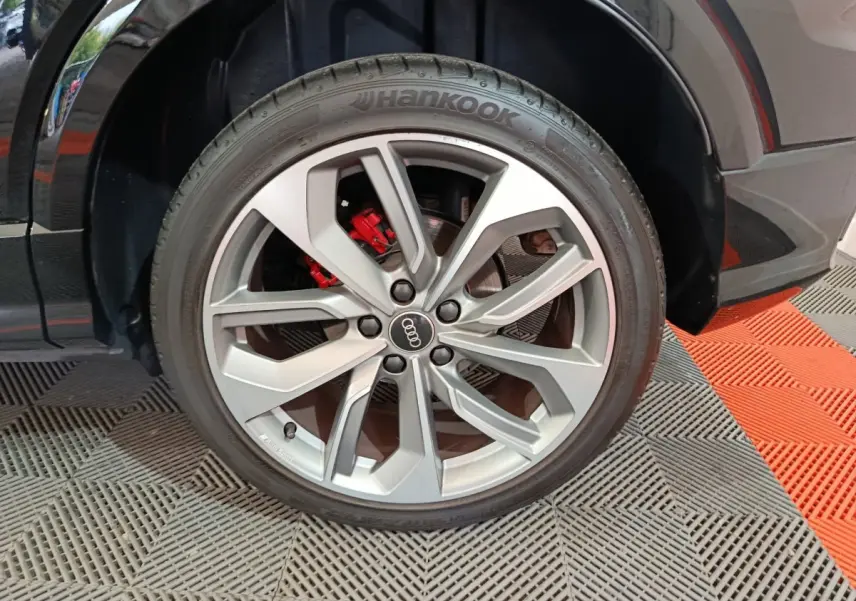 Gros plan sur la roue avant droite noire d’un Audi Q2 35 TFSI S Line Plus avec étrier de frein rouge visible.
