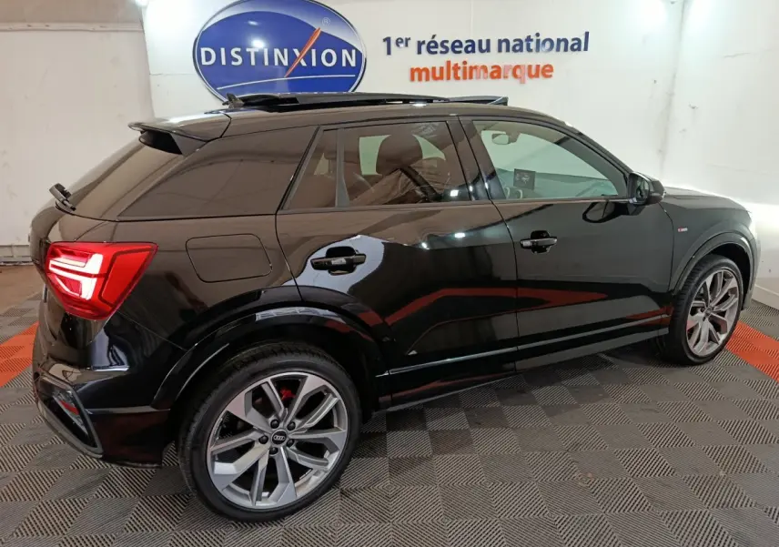 Audi Q2 35 TFSI S Line Plus noire vue de profil côté gauche avec jantes alliage et feux arrière allumés