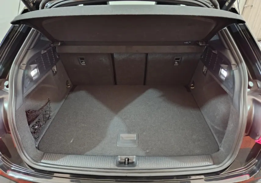 Coffre ouvert vu de l'arrière d'un Audi Q2 noir 2022, espace de chargement propre et éclairé.
