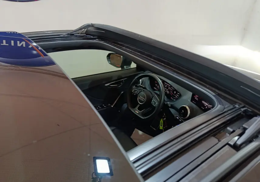 Vue intérieure côté conducteur d'un Audi Q2 noir 2022, volant cuir et tableau de bord numérique lumineux.