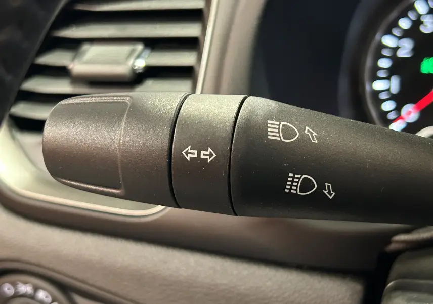 Gros plan sur la manette de clignotants et feux du tableau de bord intérieur du Jeep Renegade gris graphite 2023.