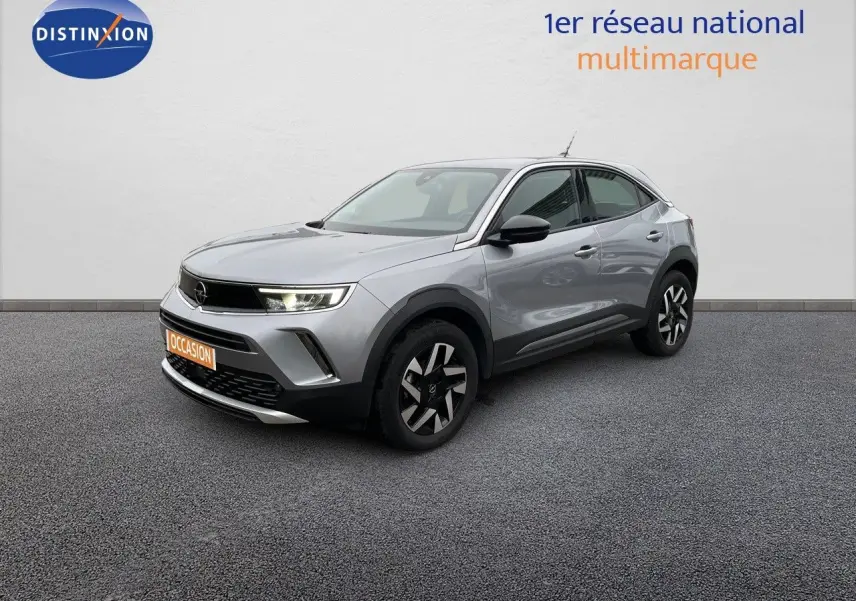 Opel Mokka gris Artens métal en 3/4 avant droit avec jantes noires et phares LED allumés sur fond neutre.
