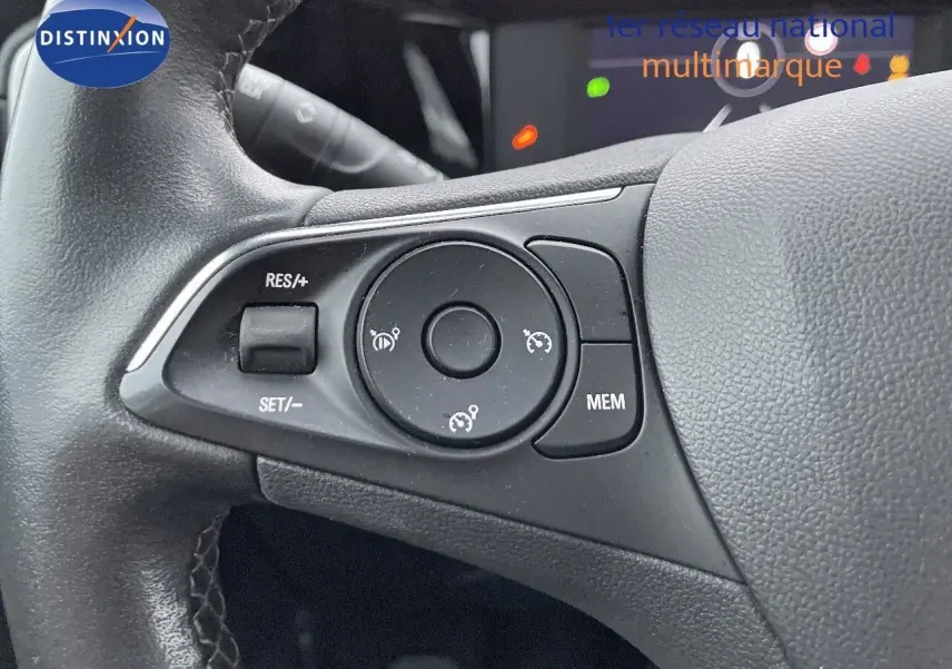 Gros plan sur les commandes de régulateur de vitesse au volant en cuir noir de l'Opel Mokka gris Artens 2021.