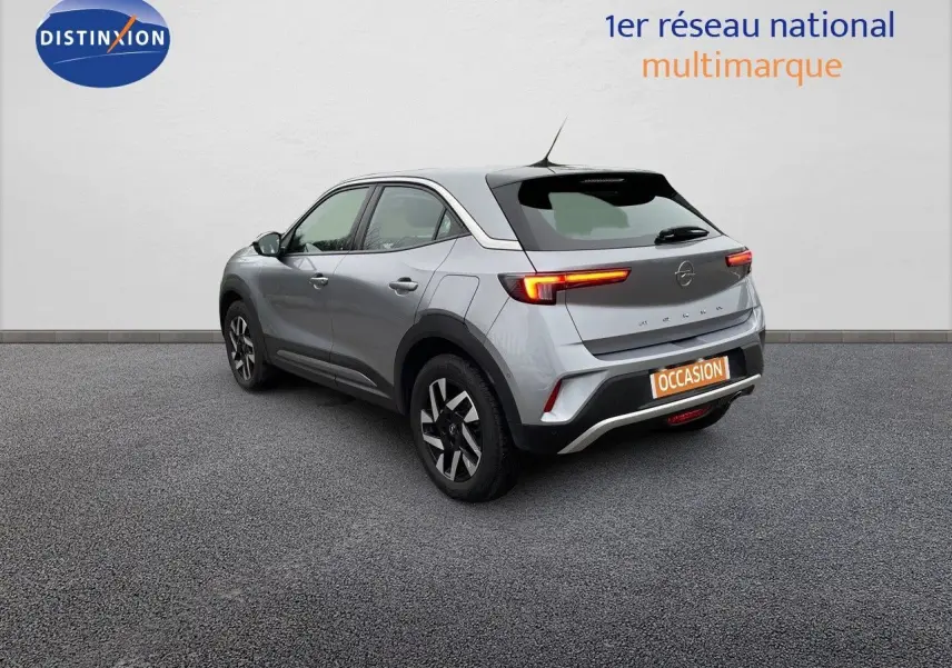 Opel Mokka gris Artens métal vue 3/4 arrière côté gauche, feux arrière allumés et jantes alliage noires.