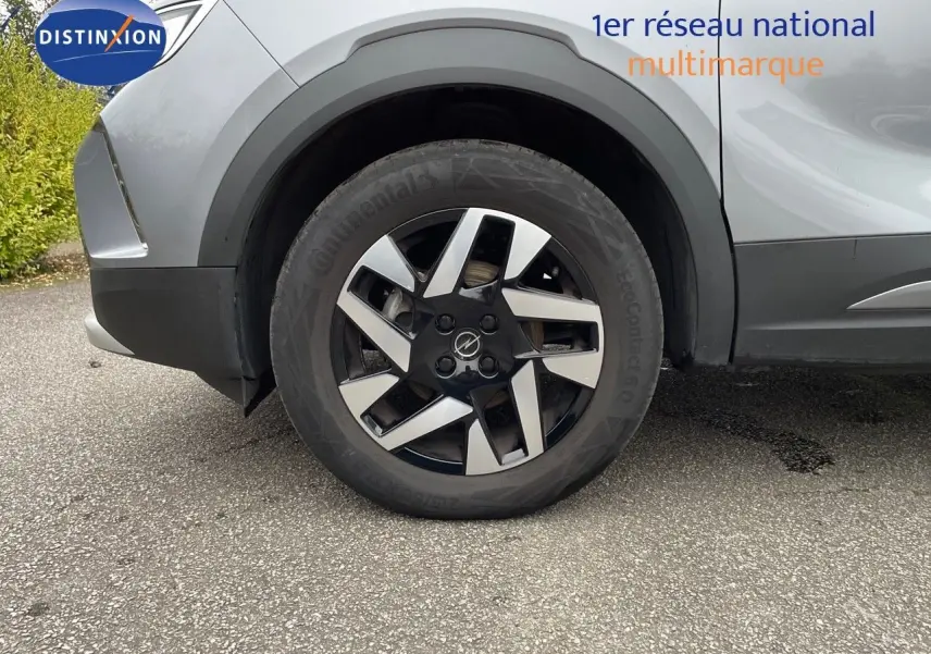Gros plan sur la roue avant gauche de l'Opel Mokka gris Artens métal, mettant en valeur la jante alliage 17 pouces au design moderne.