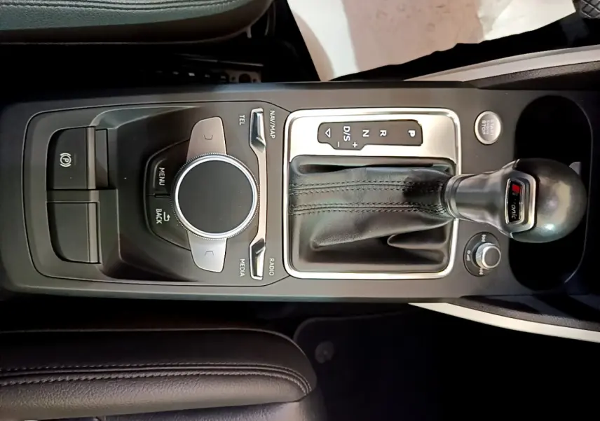 Vue rapprochée de la console centrale noire de l'Audi Q2 35 TDI 150 Design avec levier de vitesses automatique et molette de contrôle multimédia.