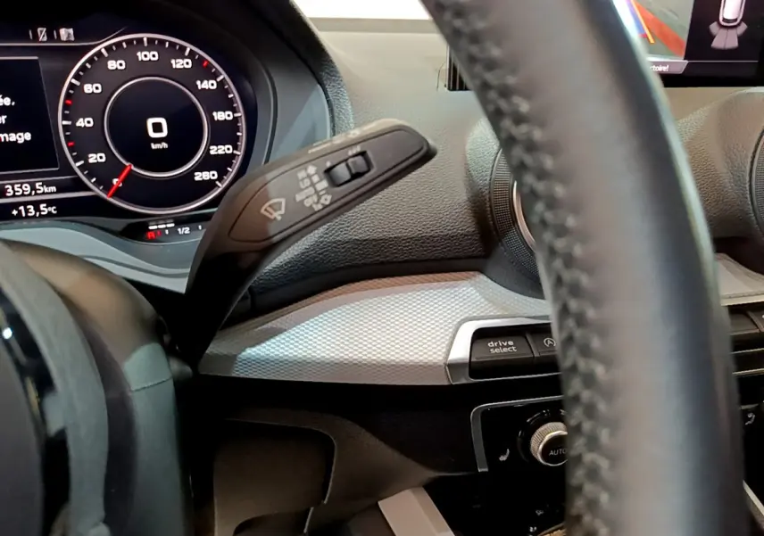 Vue rapprochée du tableau de bord et volant cuir de l'Audi Q2 gris clair, avec affichage numérique et commandes intégrées.