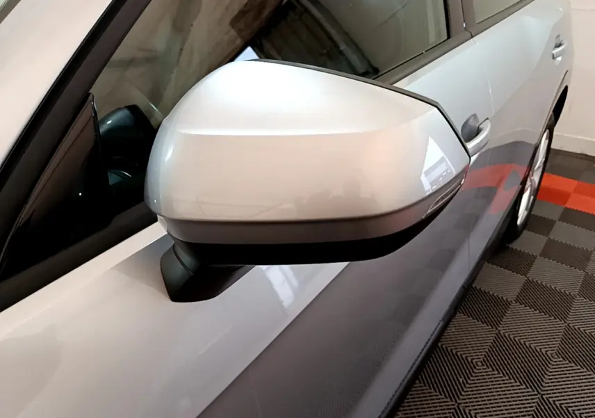 Gros plan sur le rétroviseur côté gauche gris clair de l'Audi Q2 35 TDI 150 Design, vue partielle de la portière.